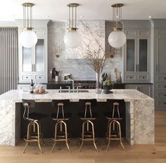 a large kitchen with marble counter tops and gold bar stools in front of an island