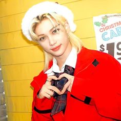 a woman wearing a santa hat and holding a cell phone in her hand while standing next to a yellow wall