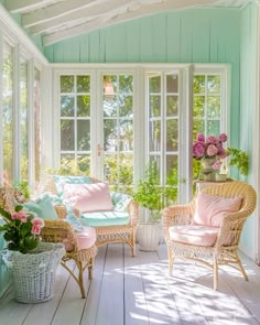 a sun room with wicker furniture and pink flowers on the window sills