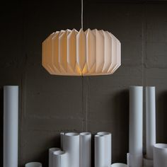 a white lamp hanging from a ceiling next to some rolls of paper on the floor