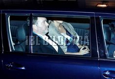 a man and woman sitting in the back seat of a car