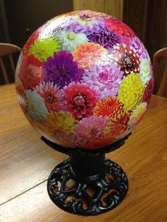 a colorful flowered globe sitting on top of a wooden table next to two chairs