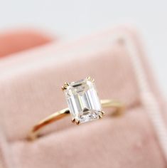 an emerald - cut diamond ring sits in a velvet box