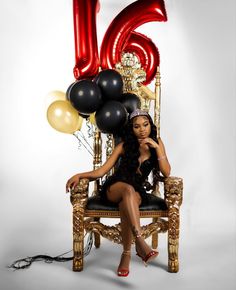 a woman is sitting on a chair with balloons in front of her and the number six behind her