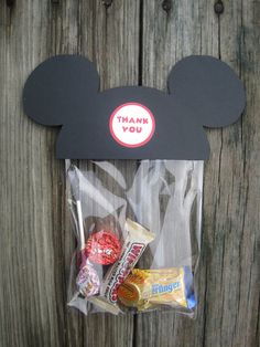 a mickey mouse treat bag with candy and candies in it, on a wooden surface