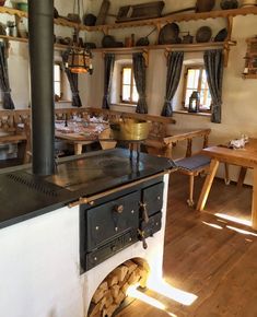 an old fashioned stove in the middle of a room with wooden tables and stools