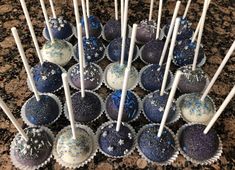 blue and white cake pops with sprinkles are arranged on a granite counter