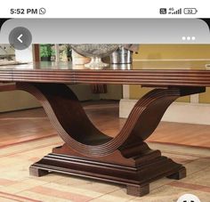 a wooden table sitting on top of a hard wood floor next to a rug and window