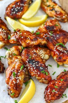 chicken wings with sesame seeds and lemon wedges on a white paper towel next to some sliced lemons