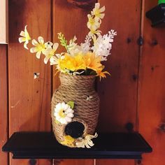 a vase filled with flowers sitting on top of a wooden shelf next to a wall