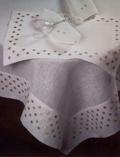 a pair of glasses sitting on top of a white table cloth covered in gold dots