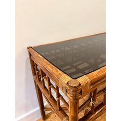 a glass top coffee table with bamboo frame and wood legs on the bottom, in front of a white wall