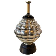 a shiny glass lamp on a black base with a gold top and metal fittings