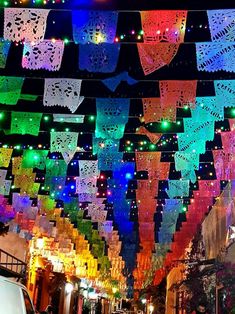 many colorful lights hanging from the ceiling above a street