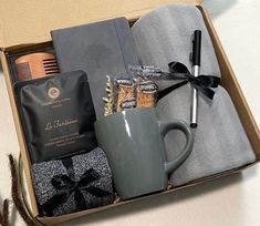 an open box containing a coffee cup, mug, and other personal care items on a table