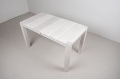 a white table sitting in the middle of a room next to a wall and floor