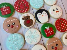 many decorated cookies are arranged on a white wooden surface with snowflakes and penguins