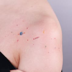 a woman's back with small tattoos on her left shoulder and the other arm