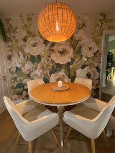 a dining room table with four chairs and a wallpapered flower design behind it