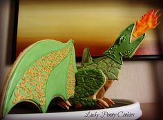 a cake shaped like a green dragon with an orange flame coming out of its mouth