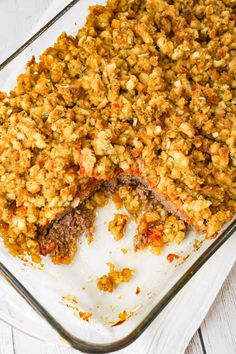 a casserole dish filled with meat and stuffing on top of a white wooden table