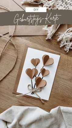 a card with hearts attached to it on top of a wooden table next to some string