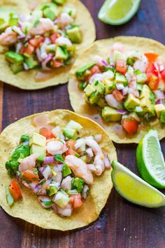 three tortillas topped with shrimp, avocado and salsa on a wooden table