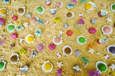 an overhead view of toys and sand on the ground, including cups with saucers in them