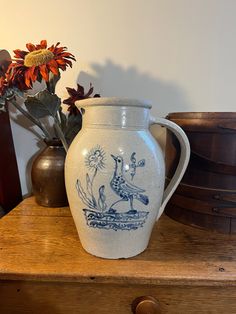 a blue and white vase sitting on top of a wooden table next to some flowers