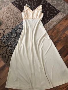 a white dress laying on top of a wooden floor next to a black and silver rug