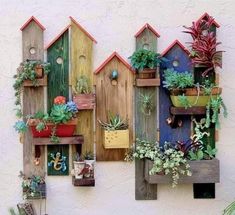 several wooden birdhouses with succulents and plants in them on the side of a building