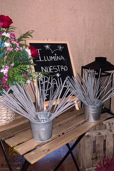 two buckets filled with flowers sitting on top of a wooden bench next to a sign