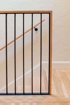 an open gate on the side of a stair case in a room with wooden floors