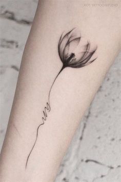 a black and white photo of a flower with the word love tattooed on it's arm