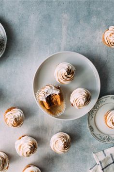 some cupcakes are sitting on plates and next to each other with frosting