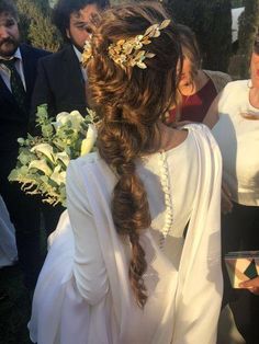 a woman in a white dress is standing next to other people and holding a bouquet