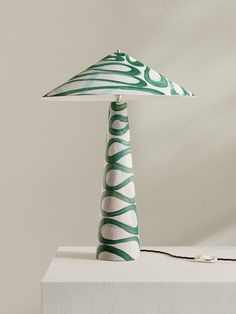 a green and white table lamp sitting on top of a white box next to a wall