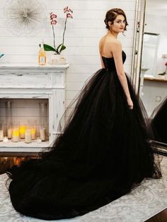 a woman standing in front of a mirror wearing a black dress