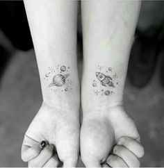 two people with matching tattoos on their arms holding each other's hands and looking at the space between them