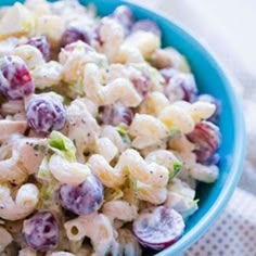 a blue bowl filled with macaroni salad on top of a white table cloth