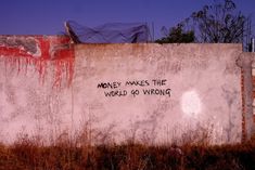 graffiti on the side of a wall that says money makes the world go wrong in black and white