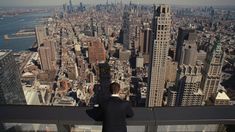 a man standing on top of a tall building looking down at the city below him