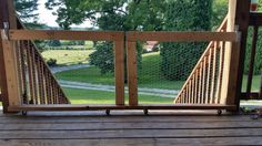 a wooden deck with railings on it and trees in the background