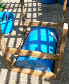 there is a blue barrel on the ground next to two buckets and a fence