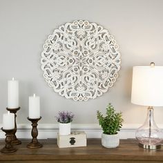 a wooden table topped with candles and vases next to a wall mounted art piece