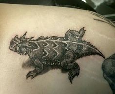 a black and white photo of a lizard tattoo on the back of a woman's shoulder