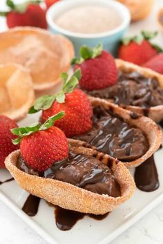 chocolate tarts and strawberries on a white plate with dipping sauce in the background