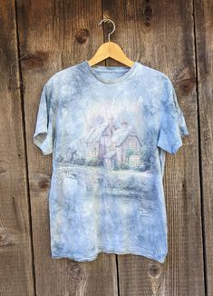 Amazing Thomas Kinkade t shirt, 1990s vintage. A perfectly distressed collectible true vintage art graphic tee! Features a blue/gray marled 'tie dye' print, and the sweetest winter cottage scene front & center. Thomas Kinkade is famous for his idyllic pastoral scenes, and this painting does not disappoint! There's nothing cooler than wearable art...;) No material labeled, feels like cotton No size labeled, fits like a Men's M, Ladies' L All measurements taken with garment lying flat, double wher Affordable Distressed Blue T-shirt, Cottagecore Cottage, Winter Cottage, Chic Art, Thomas Kinkade, Tie And Dye, Vintage Tee, Blue Tie, Guys Be Like