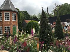 the garden is full of colorful flowers and plants with people walking around it in the background