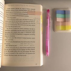 an open book next to a pink pen and eraser